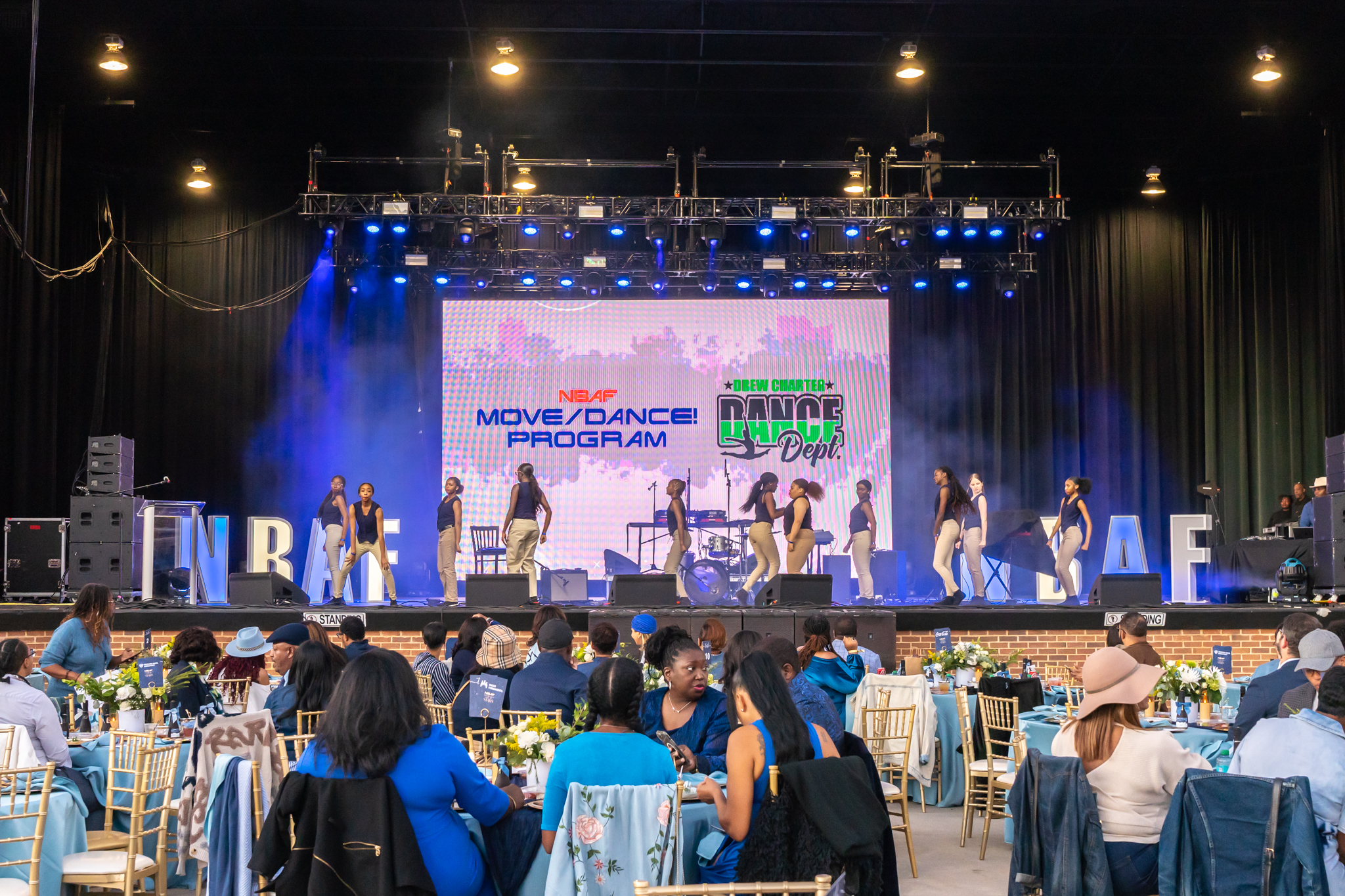 Dancers on stage with projector screen in background
