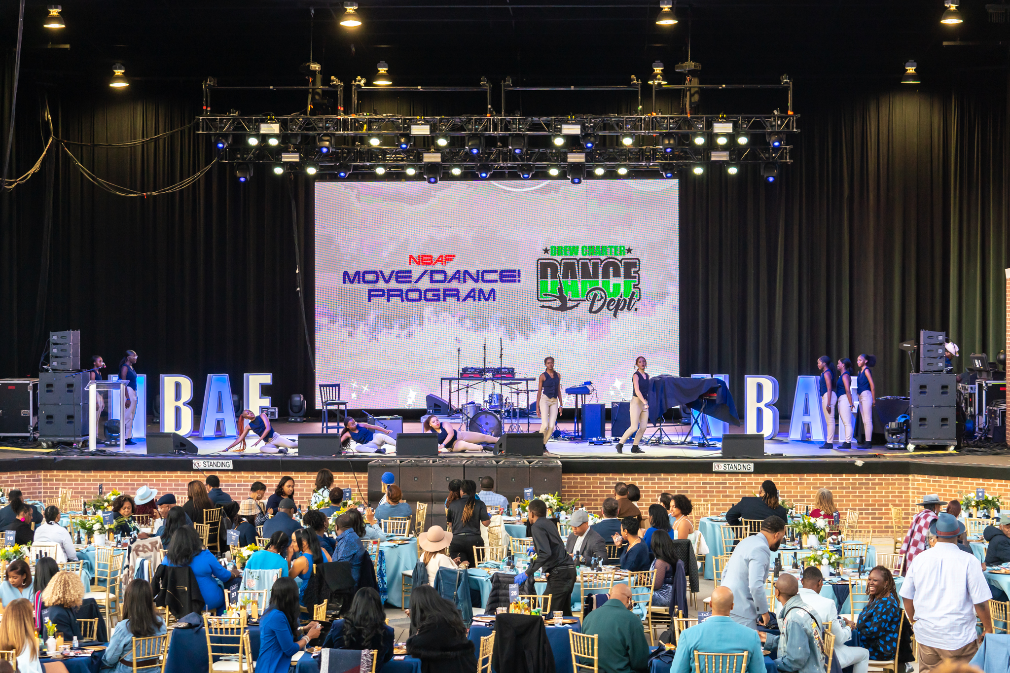 Dancers on stage with projector screen in background