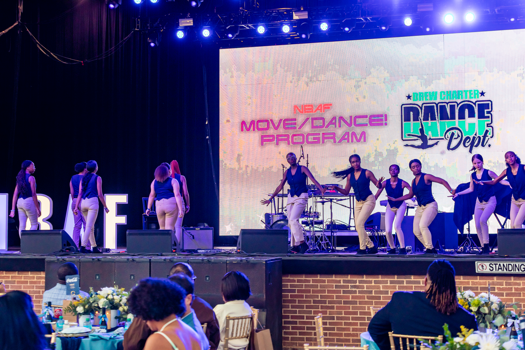 Dancers on stage with projector screen in background