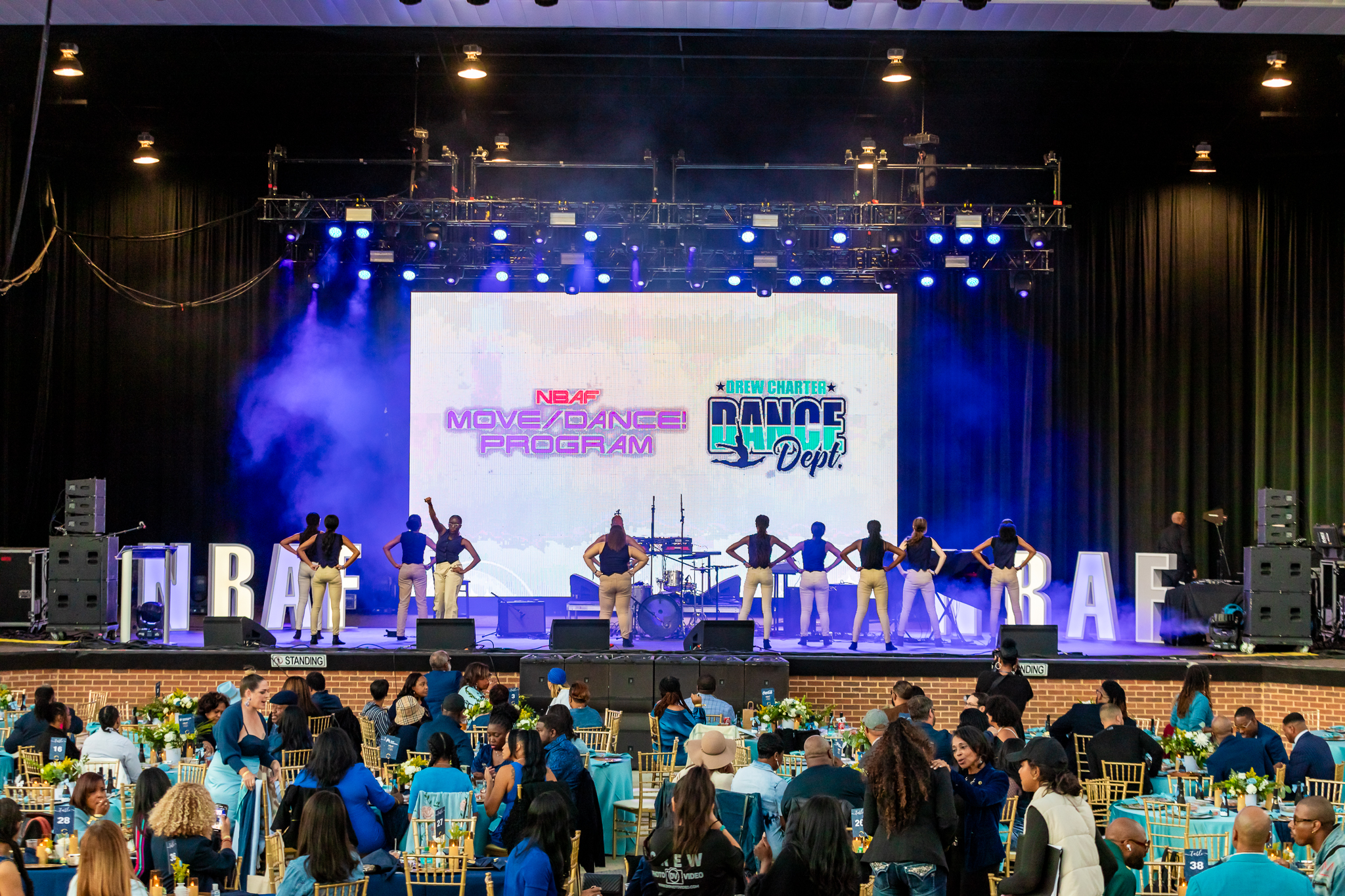 Dancers on stage with projector screen in background